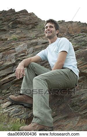 Man laughing while sitting on rock, low angle view View Large Photo Image Stock Photograph - Man laughing while sitting on rock, low angle view. Fotosearch