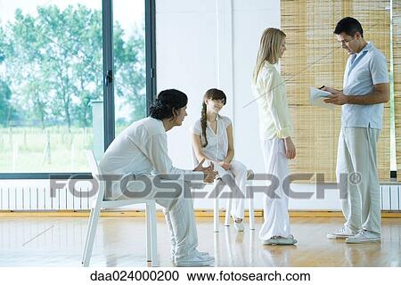 Man leading group therapy session, looking at notebook, speaking to woman View Large Photo Image Stock Image - Man leading group therapy session, looking at notebook, speaking to woman. Fotosearch