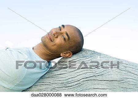 Man leaning back against wood surface, smiling at camera View Large Photo Image Stock Photo - Man leaning back against wood surface, smiling at camera. Fotosearch