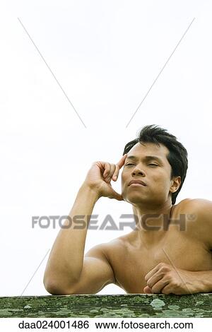 Stock Photograph - Man leaning on rail, holding head, eyes half closed. Fotosearch
