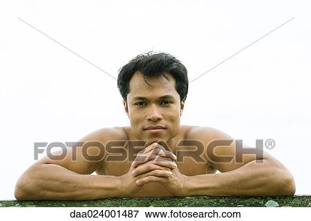 Stock Photo - Man leaning on rail, smiling at camera. Fotosearch