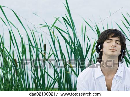Stock Photo - Man listening to headphones, eyes closed. Fotosearch