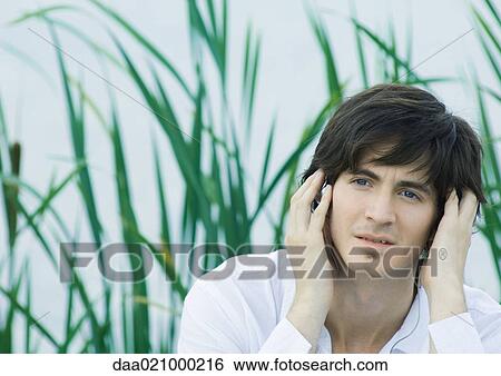 Man listening to headphones, hands over ears View Large Photo Image Stock Photograph - Man listening to headphones, hands over ears. Fotosearch