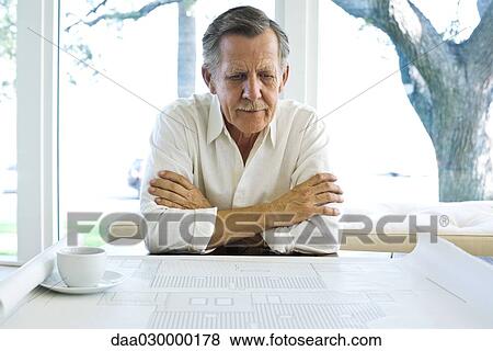 Man looking at blueprint, coffee cup nearby View Large Photo Image Stock Photo - Man looking at blueprint, coffee cup nearby. Fotosearch