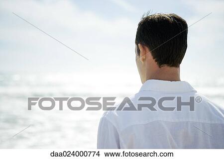 Man looking at ocean, rear view View Large Photo Image Picture - Man looking at ocean, rear view. Fotosearch