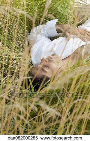 Man lying in tall grass with eyes closed View Large Photo Image Stock Photography - Man lying in tall grass with eyes closed. Fotosearch