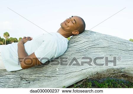 Man lying on back on wood surface, eyes closed, smiling View Large Photo Image Stock Photo - Man lying on back on wood surface, eyes closed, smiling. Fotosearch