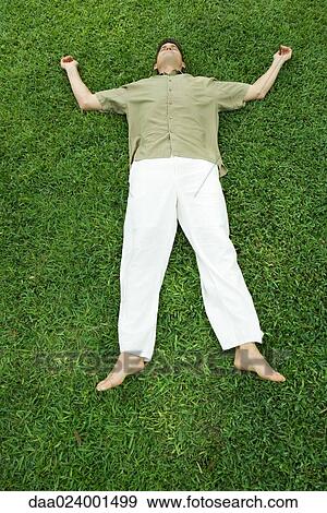 Man lying on grass, full length View Large Photo Image Stock Photo - Man lying on grass, full length. Fotosearch