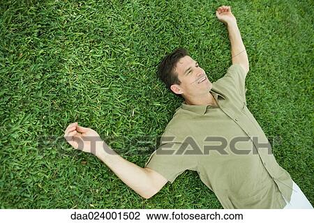 Man lying on grass, smiling View Large Photo Image Stock Image - Man lying on grass, smiling. Fotosearch