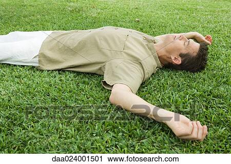 Stock Image - Man lying on grass. Fotosearch