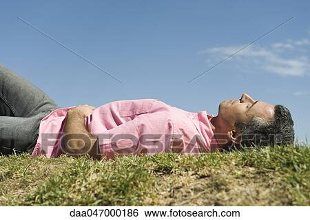 Man lying on grass View Large Photo Image Stock Photograph - Man lying on grass. Fotosearch