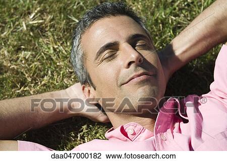 Man lying on grass with hands behind head and eyes closed View Large Photo Image Stock Image - Man lying on grass with hands behind head and eyes closed. Fotosearch