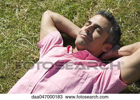 Man lying on grass with hands behind head and eyes closed View Large Photo Image Stock Image - Man lying on grass with hands behind head and eyes closed. Fotosearch