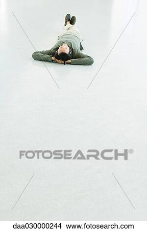 Man lying on the ground, listening to headphones View Large Photo Image Picture - Man lying on the ground, listening to headphones. Fotosearch