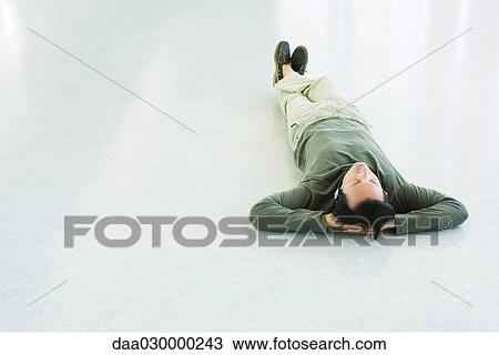 Man lying on the ground, listening to headphones View Large Photo Image Stock Image - Man lying on the ground, listening to headphones. Fotosearch