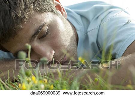 Man napping on meadow, close-up View Large Photo Image Stock Photo - Man napping on meadow, close-up. Fotosearch