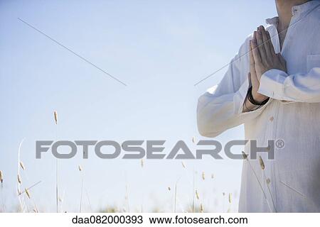 Stock Image - Man outdoors with hands clasped in prayer, cropped. Fotosearch
