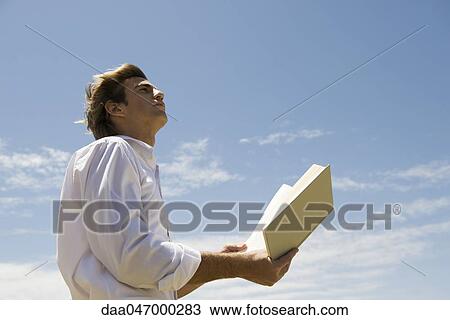 Man outdoors with open book, looking contemplatively up at sky View Large Photo Image Stock Image - Man outdoors with open book, looking contemplatively up at sky. Fotosearch