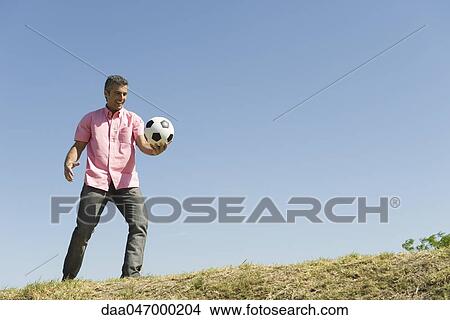 Man playing with soccer ball outdoors, smiling View Large Photo Image Picture - Man playing with soccer ball outdoors, smiling. Fotosearch