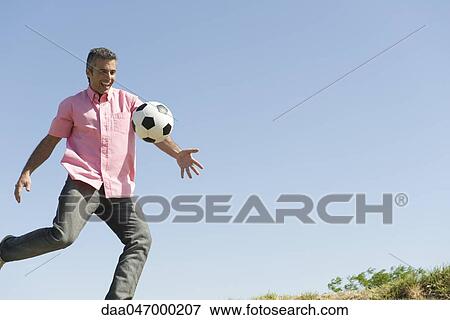 Man playing with soccer ball outdoors, smiling View Large Photo Image Stock Photo - Man playing with soccer ball outdoors, smiling. Fotosearch
