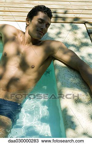 Stock Image - Man relaxing in swimming pool, eyes closed. Fotosearch