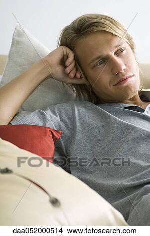 Man relaxing on pillows, looking away in thought View Large Photo Image Picture - Man relaxing on pillows, looking away in thought. Fotosearch