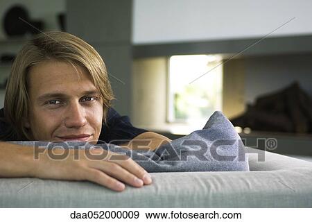 Man relaxing on sofa, smiling, portrait View Large Photo Image Stock Photo - Man relaxing on sofa, smiling, portrait. Fotosearch