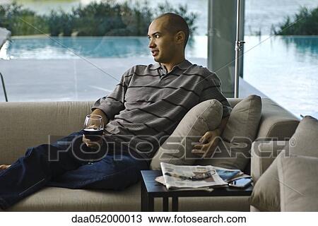 Man relaxing on sofa with glass of wine View Large Photo Image Stock Image - Man relaxing on sofa with glass of wine. Fotosearch