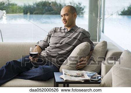 Stock Photograph - Man relaxing on sofa with glass of wine. Fotosearch