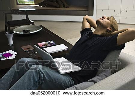 Man relaxing on sofa with laptop computer on lap View Large Photo Image Stock Image - Man relaxing on sofa with laptop computer on lap. Fotosearch