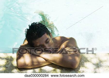 Man resting head on arms on side of swimming pool, eyes closed View Large Photo Image Picture - Man resting head on arms on side of swimming pool, eyes closed. Fotosearch
