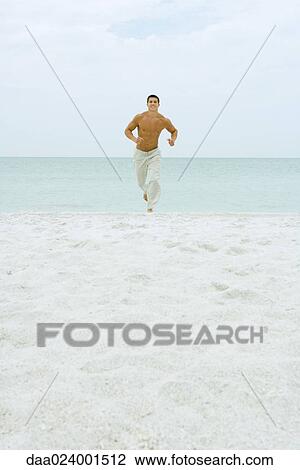Man running on beach, facing camera, ocean in background, full length View Large Photo Image Stock Image - Man running on beach, facing camera, ocean in background, full length. Fotosearch