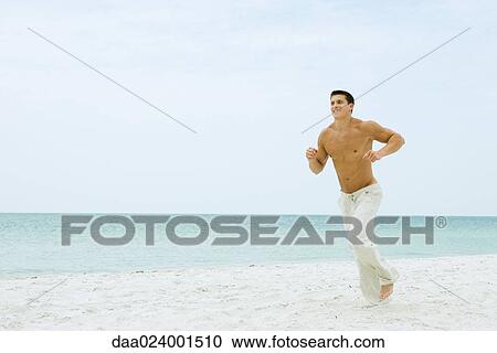 Man running on beach, full length View Large Photo Image Stock Image - Man running on beach, full length. Fotosearch