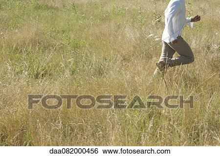 Stock Photograph - Man running through field, mid section. Fotosearch