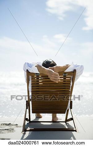 Man sitting in deck chair, facing sea, rear view View Large Photo Image Stock Image - Man sitting in deck chair, facing sea, rear view. Fotosearch