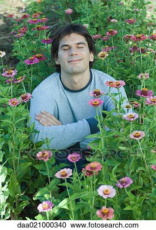 Man sitting in flowers, eyes closed View Large Photo Image Stock Image - Man sitting in flowers, eyes closed. Fotosearch