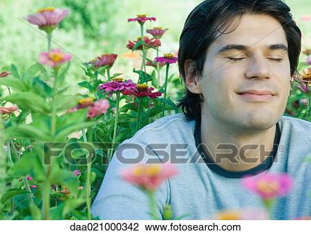 Man sitting in flowers, eyes closed View Large Photo Image Stock Image - Man sitting in flowers, eyes closed. Fotosearch