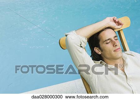 Man sitting in lounge chair beside swimming pool, eyes closed, high angle view View Large Photo Image Stock Image - Man sitting in lounge chair beside swimming pool, eyes closed, high angle view. Fotosearch