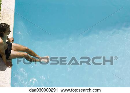 Man sitting on edge of swimming pool, soaking feet in water, high angle view View Large Photo Image Stock Image - Man sitting on edge of swimming pool, soaking feet in water, high angle view. Fotosearch