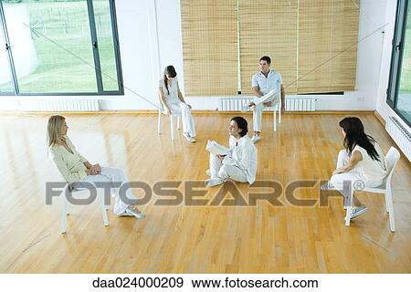 Man sitting on floor, holding book, speaking to group View Large Photo Image Stock Photo - Man sitting on floor, holding book, speaking to group. Fotosearch