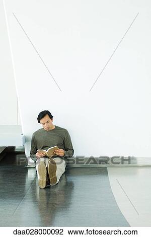 Man sitting on floor, reading book, full length View Large Photo Image Stock Image - Man sitting on floor, reading book, full length. Fotosearch