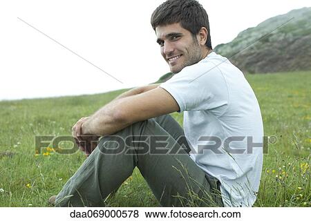 Man sitting on meadow, portrait View Large Photo Image Stock Photo - Man sitting on meadow, portrait. Fotosearch