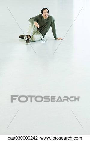 Man sitting on the ground, listening to MP3 player with headphones View Large Photo Image Stock Image - Man sitting on the ground, listening to MP3 player with headphones. Fotosearch