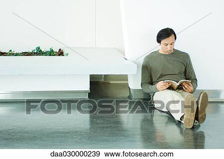 Man sitting on the ground, reading book, full length View Large Photo Image Stock Photo - Man sitting on the ground, reading book, full length. Fotosearch