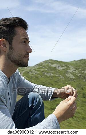 Man sitting outdoors, looking away in thought View Large Photo Image Stock Image - Man sitting outdoors, looking away in thought. Fotosearch