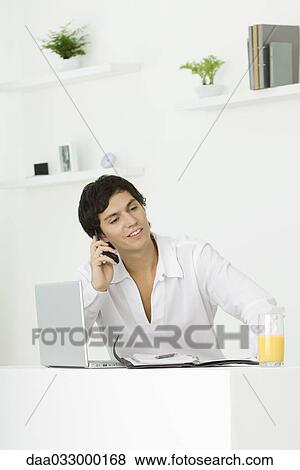 Man sitting, using cell phone, looking away, smiling View Large Photo Image Stock Photo - Man sitting, using cell phone, looking away, smiling. Fotosearch