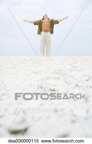 Man standing at the beach with arms out, head back View Large Photo Image Stock Photography - Man standing at the beach with arms out, head back. Fotosearch