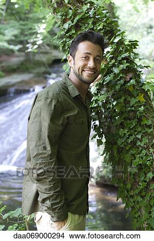 Man standing beside ivy covered tree, portrait View Large Photo Image Picture - Man standing beside ivy covered tree, portrait. Fotosearch