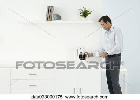 Man standing by counter, getting coffee, side view View Large Photo Image Stock Photography - Man standing by counter, getting coffee, side view. Fotosearch