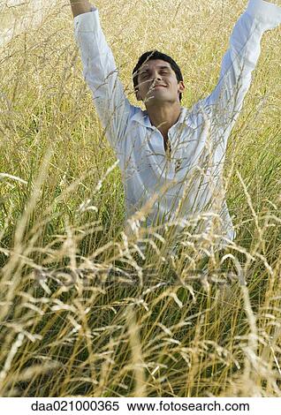 Man standing in field, raising arms, eyes closed View Large Photo Image Stock Photography - Man standing in field, raising arms, eyes closed. Fotosearch